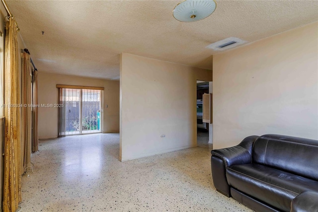 living area featuring a textured ceiling, speckled floor, and baseboards