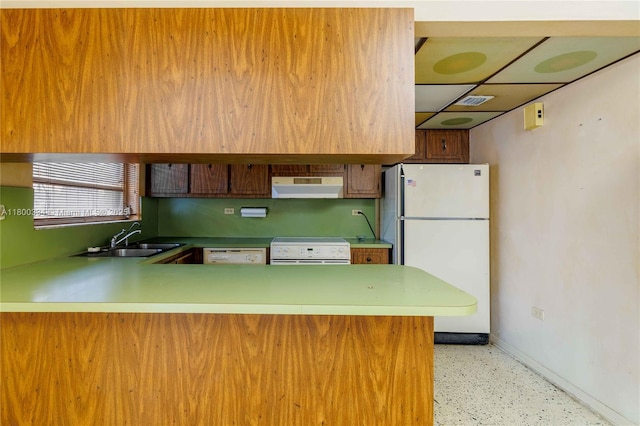 kitchen featuring white appliances, ventilation hood, a sink, baseboards, and a peninsula