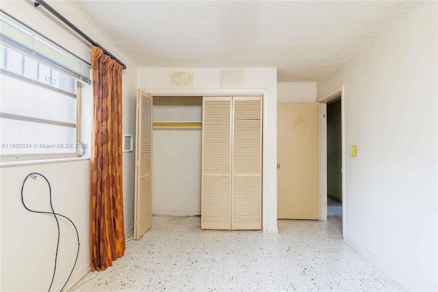 unfurnished bedroom with a closet, a textured ceiling, and baseboards