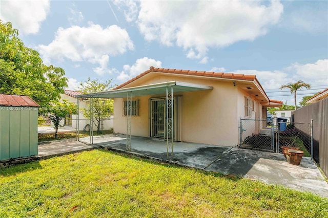 back of house with a gate, stucco siding, a tiled roof, and a patio