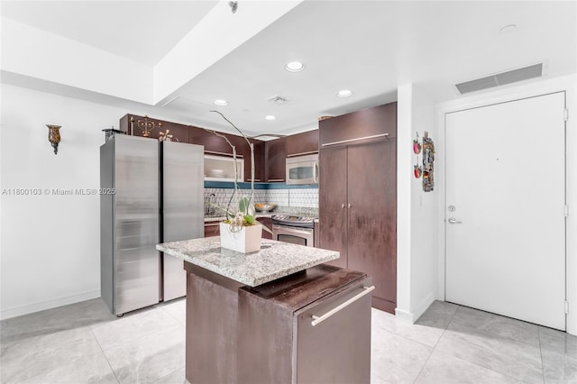 kitchen featuring appliances with stainless steel finishes, baseboards, a kitchen island, tasteful backsplash, and recessed lighting