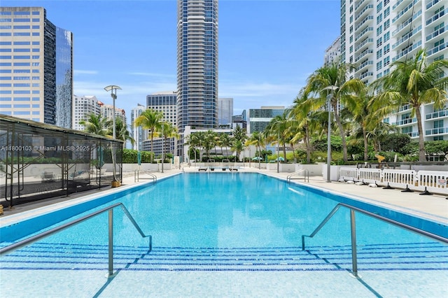 community pool with a city view and fence