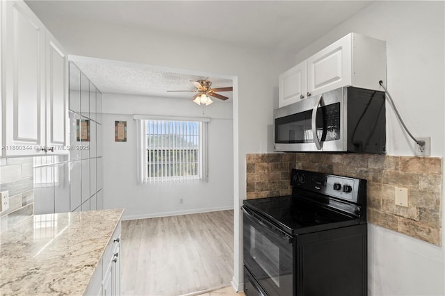 300 SW 134th Way Unit 413E, Pembroke Pines, FL 33027 - kitchen featuring stainless steel microwave, black electric range, decorative backsplash, a ceiling fan, and white cabinetry