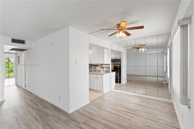 300 SW 134th Way Unit 413E, Pembroke Pines, FL 33027 - unfurnished living room featuring a ceiling fan, light wood finished floors, a textured ceiling, and baseboards
