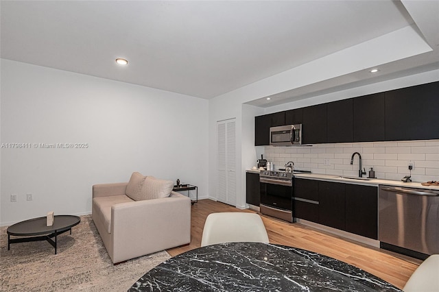 398 NE 5th St Unit 2415, Miami, FL 33132 - kitchen with stainless steel appliances, dark cabinetry, a sink, light countertops, and tasteful backsplash