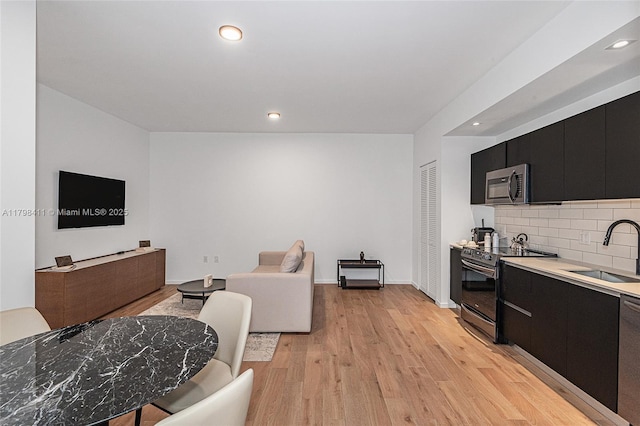 398 NE 5th St Unit 2415, Miami, FL 33132 - kitchen with a sink, dark cabinetry, appliances with stainless steel finishes, light wood finished floors, and recessed lighting