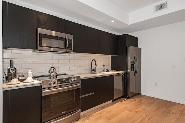 398 NE 5th St Unit 2415, Miami, FL 33132 - kitchen featuring stainless steel appliances, dark cabinets, a sink, light countertops, and backsplash