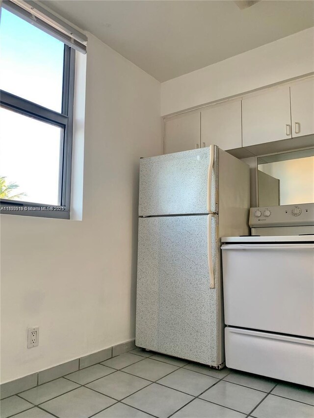 9225 Collins Ave Unit 307, Surfside, FL 33154 - kitchen featuring white appliances, light tile patterned flooring, healthy amount of natural light, and white cabinetry