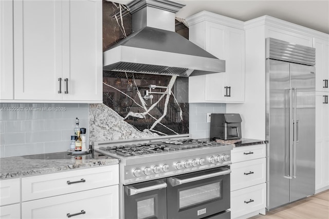 1220 Coury Dr, Key Colony, FL 33051 - kitchen featuring high quality appliances, wall chimney exhaust hood, tasteful backsplash, light stone counters, and white cabinets
