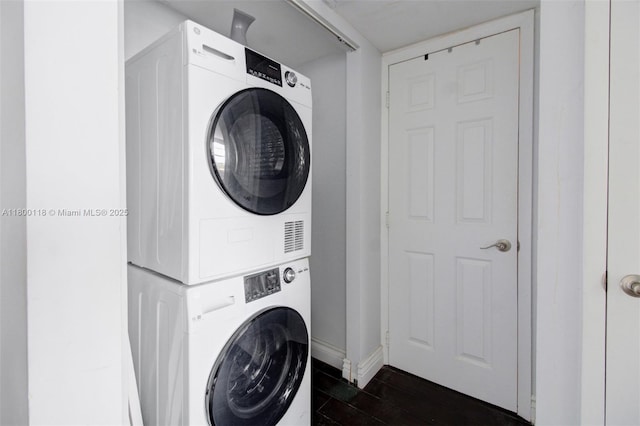6770 Indian Creek Dr Unit 6O, Miami Beach, FL 33141 - clothes washing area featuring stacked washing machine and dryer, dark wood-style floors, and baseboards