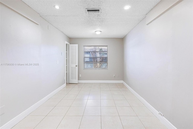 unfurnished room with a textured ceiling, recessed lighting, light tile patterned flooring, and baseboards