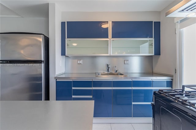 301 Jefferson Ave Unit 4D, Miami Beach, FL 33139 - kitchen with stainless steel counters, freestanding refrigerator, black range with gas stovetop, and glass insert cabinets