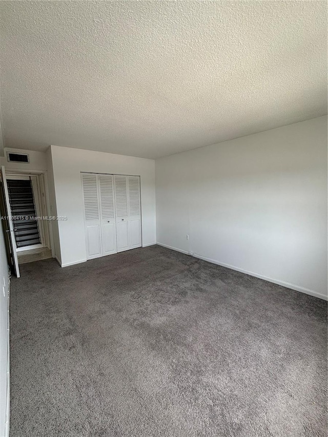 400 Kings Point Dr Unit 309, Sunny Isles Beach, FL 33160 - unfurnished bedroom featuring dark colored carpet, a textured ceiling, baseboards, and a closet
