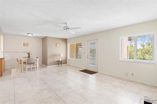 entrance foyer featuring a ceiling fan, a textured ceiling, light tile patterned floors, and baseboards