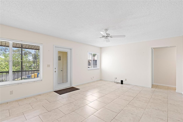 unfurnished room with ceiling fan, a textured ceiling, light tile patterned floors, and baseboards