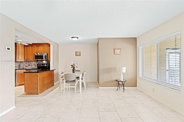 322 Pine Ridge Cir Unit A-2, Green Acres, FL 33463 - kitchen featuring appliances with stainless steel finishes, a textured ceiling, decorative backsplash, brown cabinetry, and dark countertops