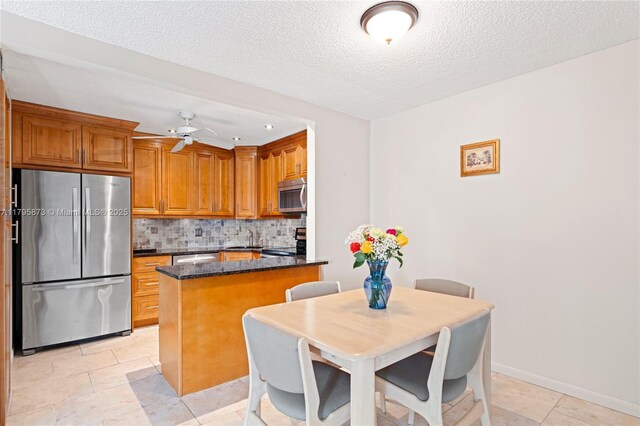 kitchen featuring stainless steel appliances, decorative backsplash, brown cabinets, ceiling fan, and light tile patterned floors