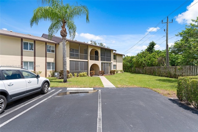 322 Pine Ridge Cir Unit A-2, Green Acres, FL 33463 - view of building exterior with uncovered parking and fence