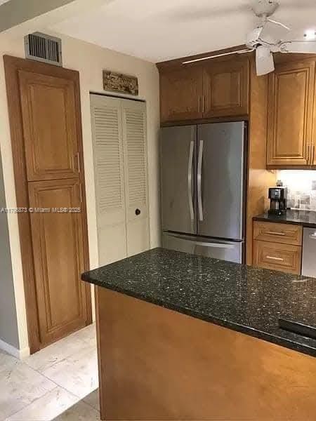 322 Pine Ridge Cir Unit A-2, Green Acres, FL 33463 - kitchen with freestanding refrigerator, dark stone counters, brown cabinetry, and a ceiling fan