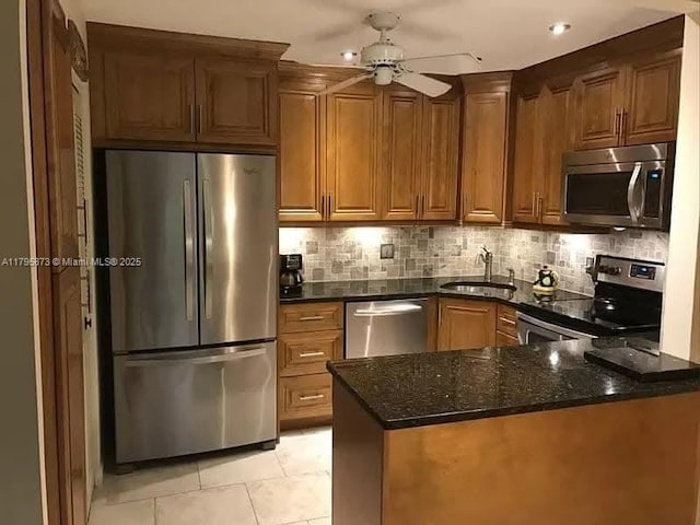 322 Pine Ridge Cir Unit A-2, Green Acres, FL 33463 - kitchen with stainless steel appliances, a peninsula, dark stone counters, a ceiling fan, and light tile patterned floors