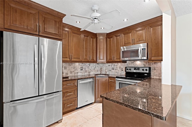 322 Pine Ridge Cir Unit A-2, Green Acres, FL 33463 - kitchen with stainless steel appliances, a peninsula, brown cabinets, dark stone countertops, and a textured ceiling