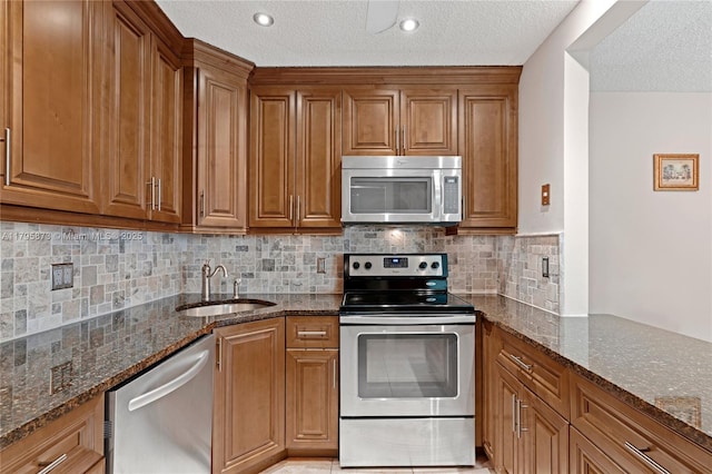 322 Pine Ridge Cir Unit A-2, Green Acres, FL 33463 - kitchen with stainless steel appliances, brown cabinetry, dark stone counters, a textured ceiling, and decorative backsplash