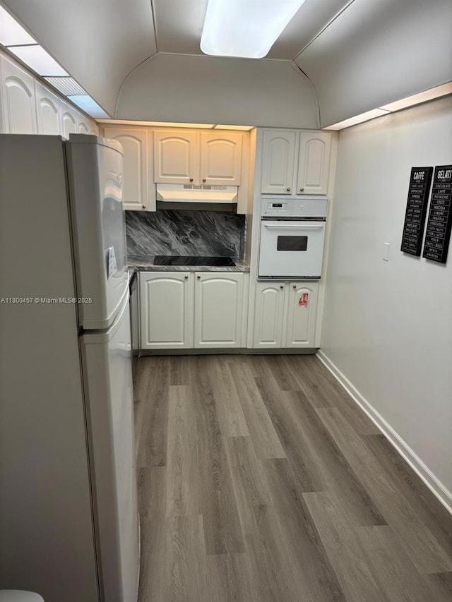 3901 S Ocean Dr Unit 2Z, Hollywood, FL 33019 - kitchen with white appliances, under cabinet range hood, dark wood-style floors, vaulted ceiling, and baseboards