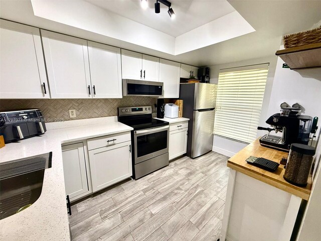 300 Promenade Dr Unit 105, Dunedin, FL 34698 - kitchen with stainless steel appliances, tasteful backsplash, light wood-type flooring, and white cabinets