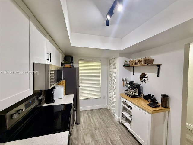 300 Promenade Dr Unit 105, Dunedin, FL 34698 - kitchen with appliances with stainless steel finishes, open shelves, white cabinetry, light wood finished floors, and baseboards