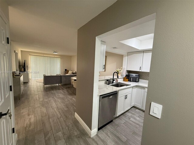 300 Promenade Dr Unit 105, Dunedin, FL 34698 - kitchen featuring dishwasher, a sink, wood finished floors, and white cabinetry