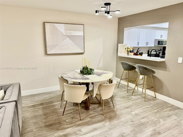 300 Promenade Dr Unit 105, Dunedin, FL 34698 - dining area featuring a chandelier, light wood-style flooring, and baseboards