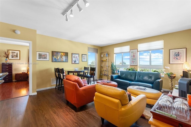 living room with dark wood finished floors, baseboards, and rail lighting