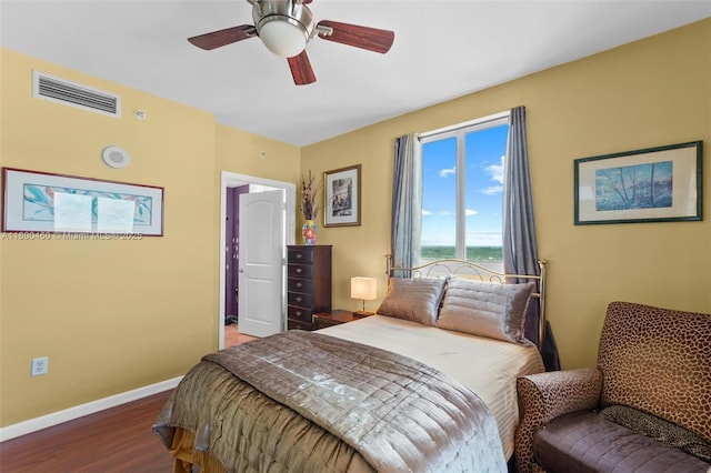 bedroom featuring a water view, wood finished floors, baseboards, and a ceiling fan