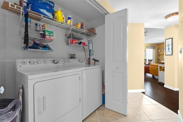 laundry area with separate washer and dryer, light tile patterned flooring, and baseboards