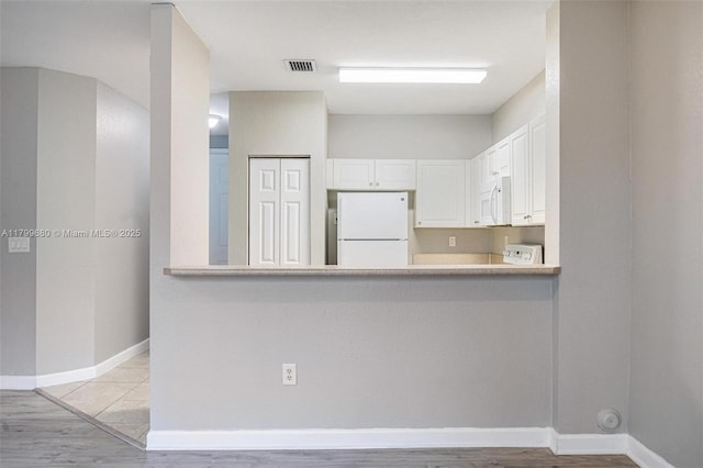 2933 SE 2nd St Unit 20, Homestead, FL 33033 - kitchen with white appliances, white cabinetry, baseboards, light wood finished floors, and light countertops