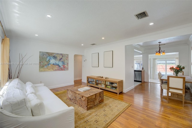 12000 NE 11th Ct, Biscayne Park, FL 33161 - living room with ornamental molding, a chandelier, arched walkways, light wood finished floors, and baseboards