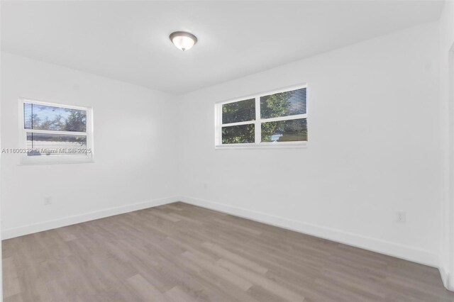 3051 NW 77th St, Miami, FL 33147 - empty room featuring wood finished floors, plenty of natural light, and baseboards