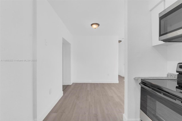 3051 NW 77th St, Miami, FL 33147 - kitchen featuring stainless steel microwave, electric stove, wood finished floors, baseboards, and light countertops