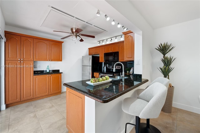 4730 SW 67th Ave Unit I1, Miami, FL 33155 - kitchen featuring appliances with stainless steel finishes, ceiling fan, a peninsula, dark stone counters, and a breakfast bar
