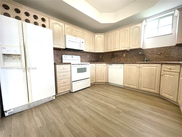 kitchen featuring white appliances, light wood finished floors, decorative backsplash, and a raised ceiling