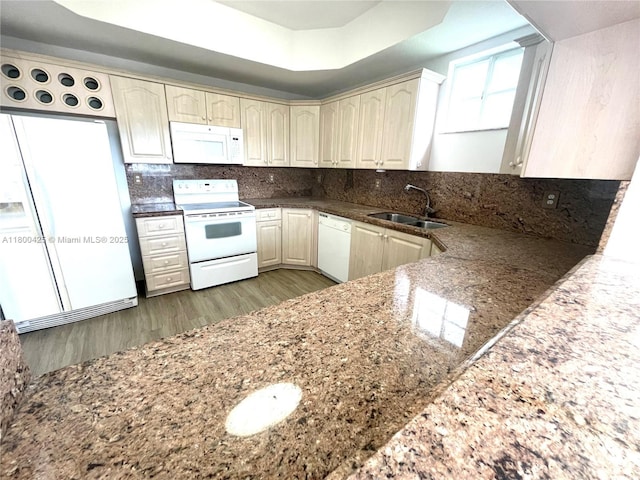 kitchen with white appliances, a sink, wood finished floors, dark stone countertops, and cream cabinetry