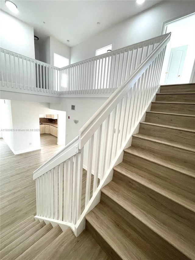 staircase with wood finished floors and recessed lighting