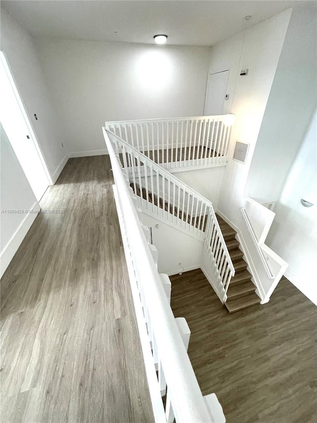 staircase featuring wood finished floors and baseboards