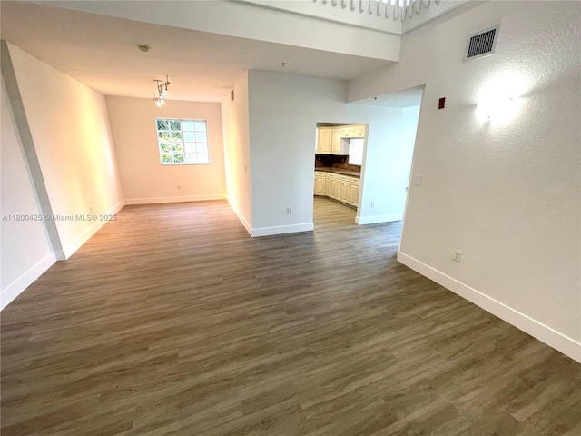 empty room featuring baseboards and dark wood-type flooring