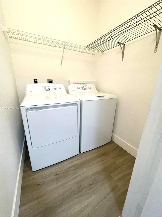 laundry area with washing machine and clothes dryer, wood finished floors, and baseboards