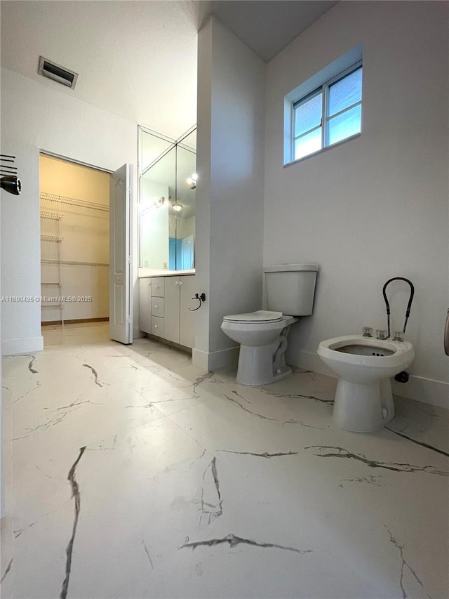 bathroom with a bidet, toilet, vanity, and marble finish floors