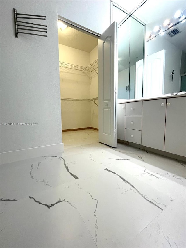 interior space featuring vanity, a walk in closet, and baseboards