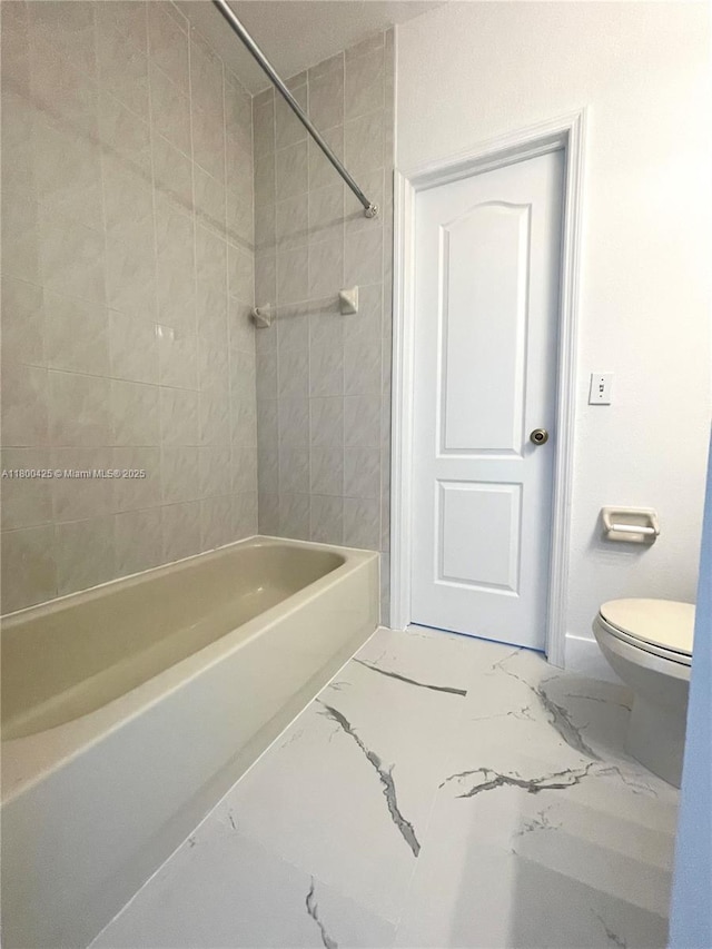 bathroom featuring marble finish floors, toilet, and  shower combination