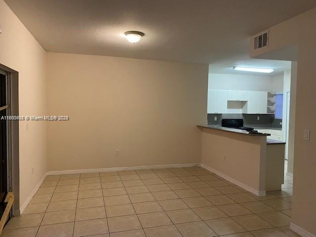 646 SW 7th Ter, Florida City, FL 33034 - kitchen featuring white cabinetry, a peninsula, range, and light tile patterned floors