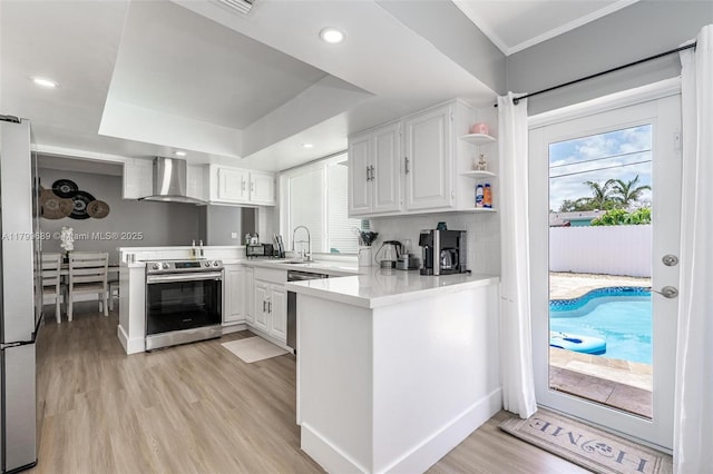 7450 Branch St, Hollywood, FL 33024 - kitchen featuring appliances with stainless steel finishes, wall chimney range hood, a peninsula, a sink, and crown molding